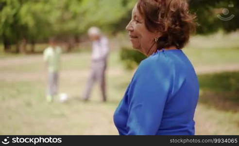 Old and young people together, seniors and children in family, generations with child and elderly persons. Sport activity, boy playing football game with grandpa, soccer in park. Happy grandma smiling