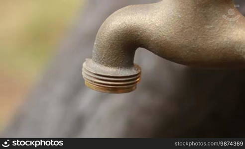 Old faucet dripping. Iron old-fashioned garden fountain. A good clip for ecology or saving money ideas. Saving water for a sustainable environment.