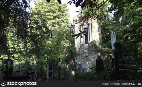 Old graveyard at the cemetery with abandoned crypt, crosses, statues