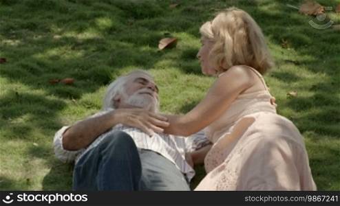Old people and romance, elderly husband and wife in love, lying on grass in park