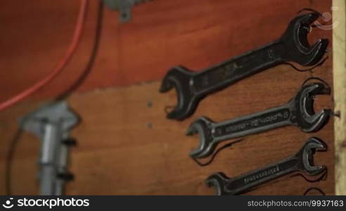 Old tools hanging on wall in workshop. Tools shelf against wall.