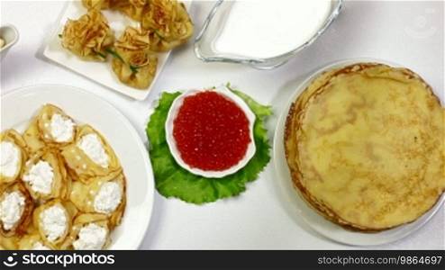 Pancakes and red caviar on dining table - a symbol of the Orthodox Shrove Tuesday. Dolly Shot