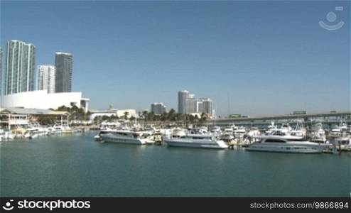 Panning view of the Bayside Marina in Miami with a lot of vessels on a sunny day.