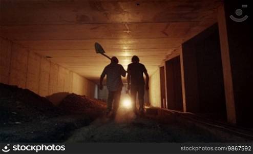 People and teamwork, team of two men at work in a new site, construction workers walking together in an underground tunnel. Part 10 of 11