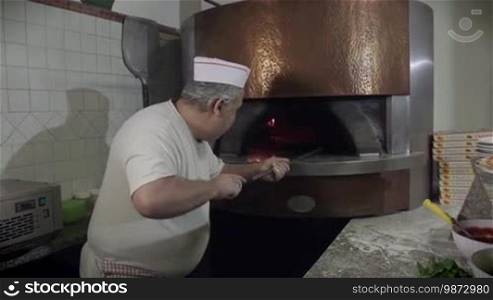 People at work, man working, food preparation, jobs, professions. Portrait of happy professional cook smiling, baker, skilled chef cooking pizza in wood oven in restaurant kitchen in Italy. 9 of 14