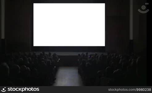 People in cinema hall. Viewers sitting in two rows watching on blank screen