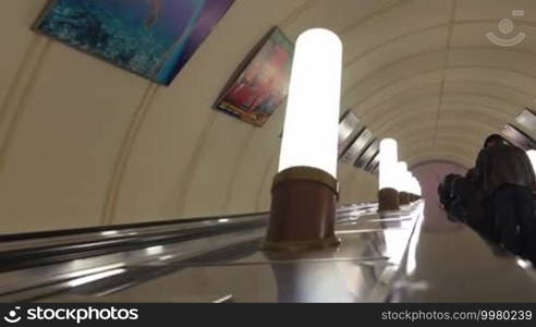 People moving up on escalator in underground. Beautiful Moscow metro station with stucco work on the ceiling