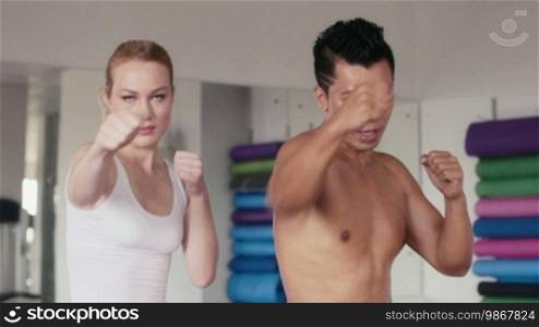 People training, working out, doing exercise in gym and fitness club, sports and martial arts. Personal trainer and girl, woman doing kickboxing for self-defense, portrait looking at camera.