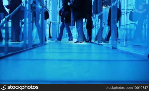 People with luggage cross a corridor to board