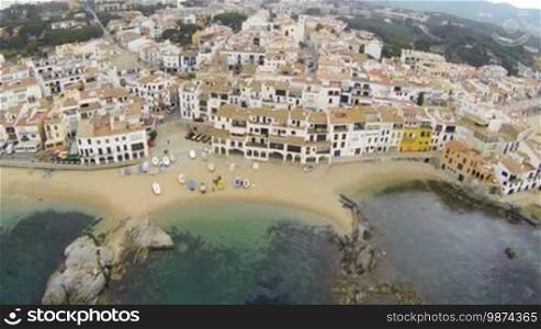 Picturesque Mediterranean fishing village in la Costa Brava, Girona. Aerial drone shot flying over the rooftops to the old center of Calella de Palafrugell. Flying over turquoise beaches with a DJI Phantom multicopter, a GoPro Hero 3 black Edition and an Arris gimbal. Typical Mediterranean landscape with white houses, tile roofs, wooden boats and pristine beaches.