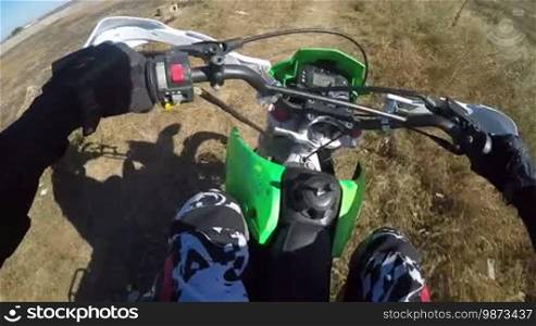 Point of View: Enduro rider riding motorcycle on dirt track