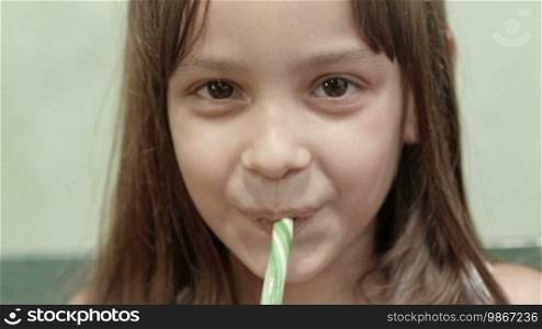 Portrait of a cute little girl with a candy bar, smiling and looking at the camera