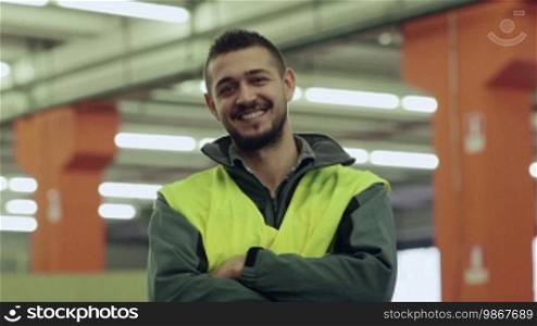 Portrait of a happy young man employed in a logistics facility smiling at the camera, people working in a warehouse, workers in the industry. 15 of 19