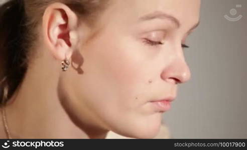 Portrait of a young adult woman applying blusher.