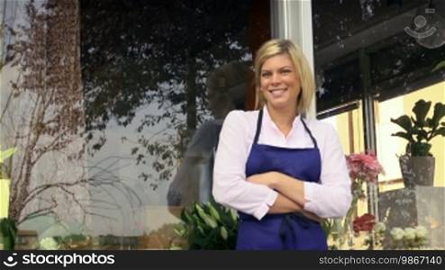 Portrait of beautiful Caucasian girl self-employed in flower shop, smiling and looking at camera. Dolly shot