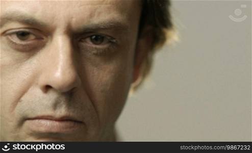 Portrait of serious Caucasian adult man staring at camera. Cropped view, gray background, copy space