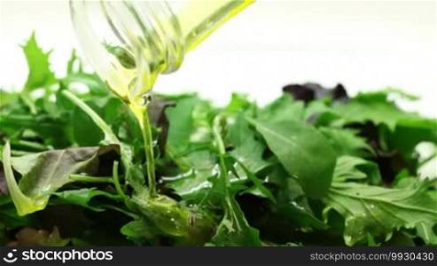 Pouring olive oil into arugula salad macro