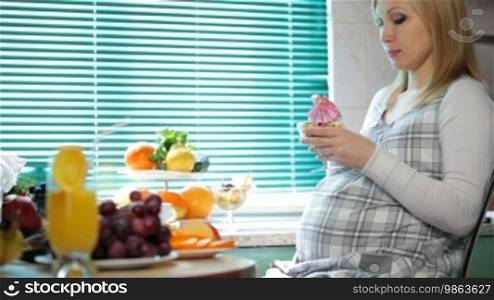 Pregnant woman at breakfast in the kitchen
