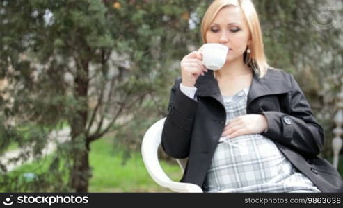 Pregnant woman drinking tea outdoors