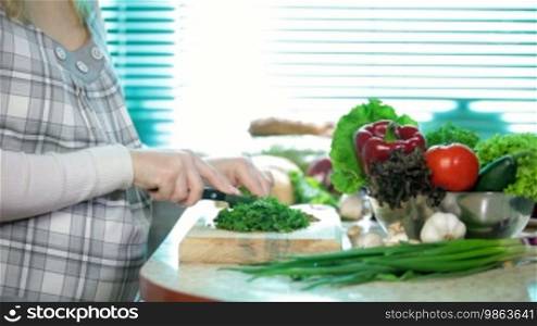 Pregnant woman slicing herb parsley