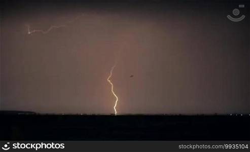 Rapid lightning strikes in the sky during a thunderstorm over the city at night