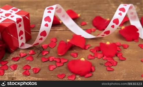Red roses with gift box and candle on wooden background. Valentine's Day concept. Love and romance.