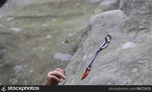 Rock climber working with rope and quickdraw during climbing