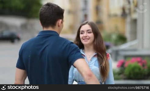 Romantic man hiding amazing bouquet of flowers for girlfriend behind his back. Excited surprised woman receiving bunch of flowers from beloved hipster teenager while meeting outdoors on romantic date. Smiling girl kissing her boyfriend.