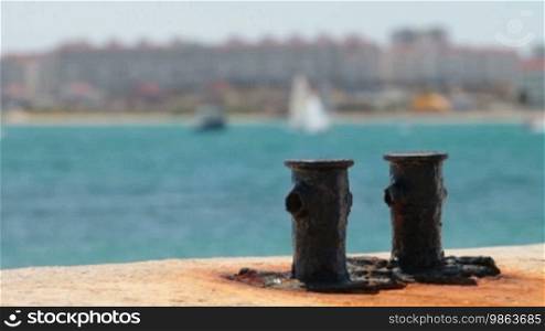 Rusty Bollard at Harbor in the background, yachts and windsurfers