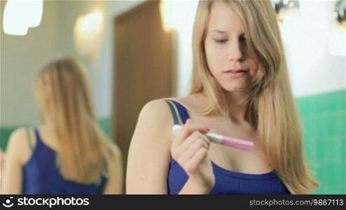 Sad young woman using pregnancy test in bathroom at home (sequence)