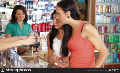 Sales representative advising a young woman in a choice of cosmetics
