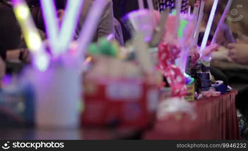 Salesman selling Chinese luminous toys at the market stall and showing them to the customers.