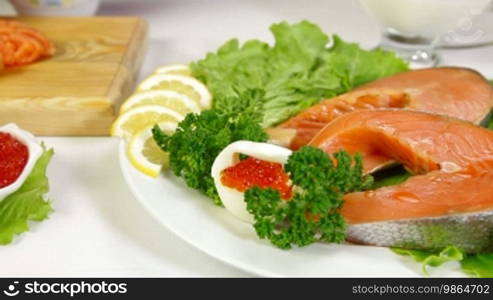 Salmon Steak and Red Caviar. In the background, a female is cutting a piece of fish. Dolly Shot Closeup.