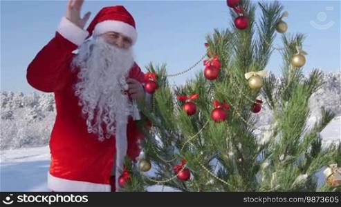 Santa Claus near Christmas tree in snow-covered winter forest