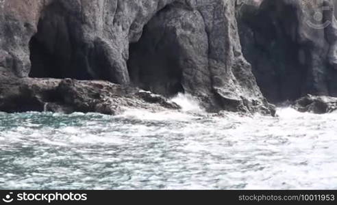 Scene shows the typical rugged coast of the Spanish volcanic island Gran Canaria with the sea in the foreground