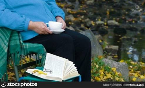 Senior woman drinking coffee. Unrecognizable person, side view