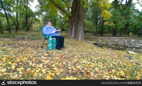 Senior Woman Reading Book in Autumn Park. Lockdown, Wide Angle
