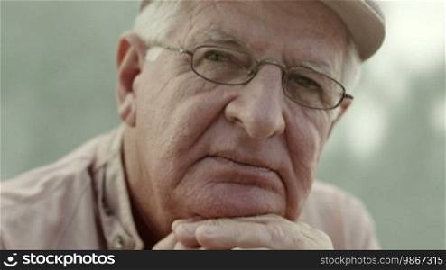 Seniors portrait of a sad elderly man with a white hat and glasses