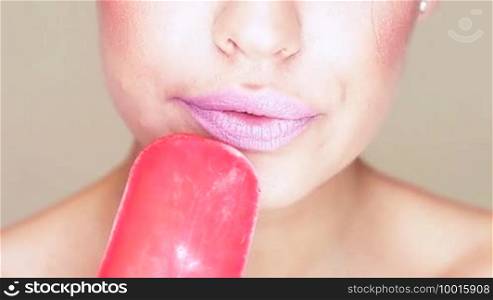 Sensual close-up of the mouth and tongue of an attractive woman licking an ice cream lolly