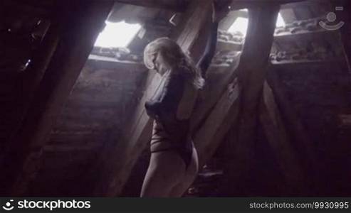 Sexy blonde woman in the abandoned building wearing bikini moving