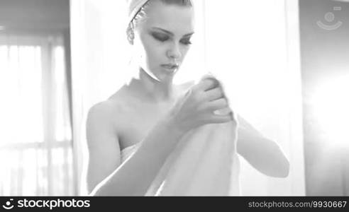 Sexy woman after shower looking at the window wearing towels