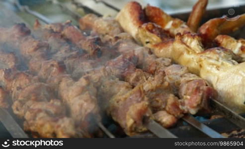 Shashlyk of pork and chicken wings being prepared on a mangal, closeup