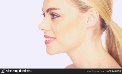 Side view of a beautiful blond woman with her long hair in a ponytail and a gentle smile, isolated on white