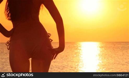 Silhouette of a beautiful woman in a bikini at sunset