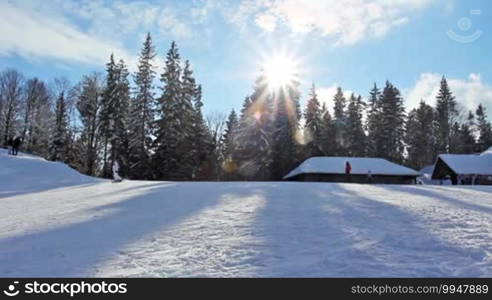 Skiers ride on slopes of mountain peaks in the evening, before sunset