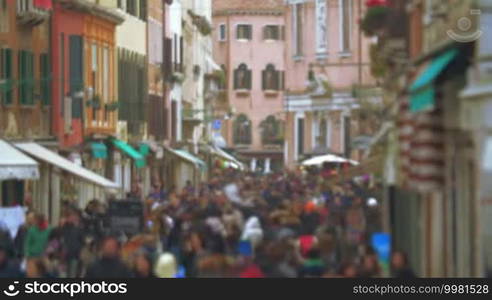 Slight defocus of busy crowded street in the city on dull day. People walking between old vintage buildings in Venice, Italy