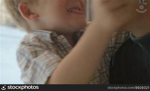 Slow motion and close-up shot of a happy little boy giving tight hugs to his beloved mother while they are traveling by train. Mom is happy to feel her son's love