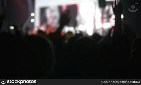 Slow motion clip of people having rest at the night concert, they stand back, jump, and clap their hands