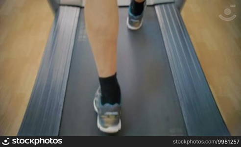 Slow motion close-up shot of male feet walking on treadmill. Every time he comes to the gym, he does some cardio