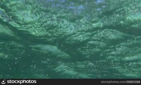 Slow motion close-up shot of sea waves and bright sun reflection. Scene with sparkling water ripples